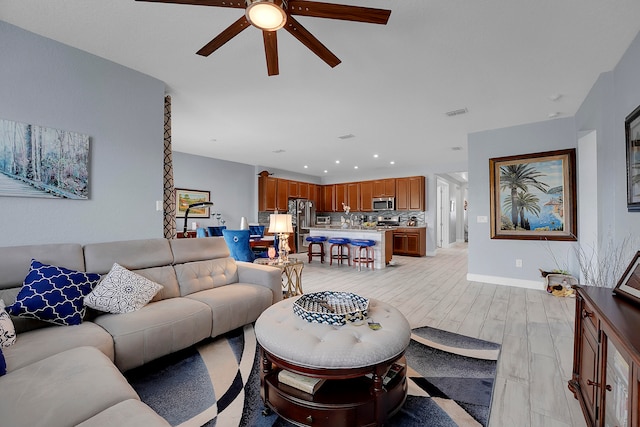 living room featuring ceiling fan and light hardwood / wood-style flooring