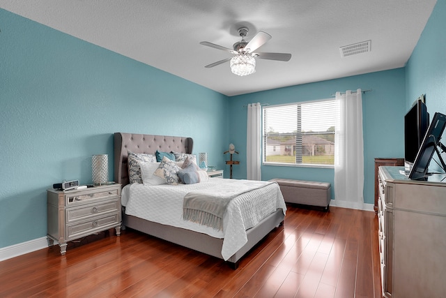 bedroom with a textured ceiling, dark hardwood / wood-style flooring, and ceiling fan