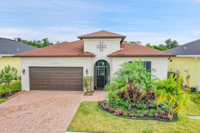 mediterranean / spanish-style home featuring a garage and a front lawn