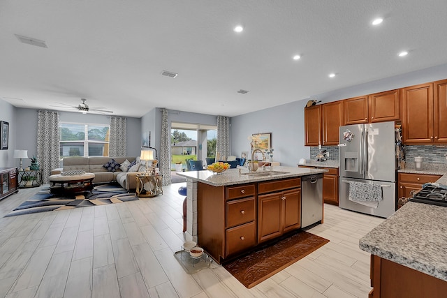 kitchen featuring a kitchen island with sink, sink, ceiling fan, light hardwood / wood-style floors, and stainless steel appliances