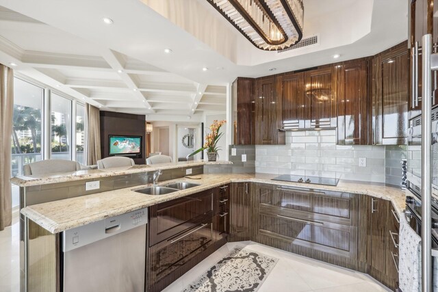 kitchen featuring light stone countertops, built in appliances, sink, and backsplash