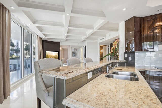 kitchen featuring light stone countertops, sink, kitchen peninsula, black electric cooktop, and decorative backsplash