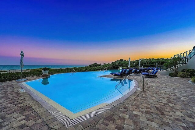 pool at dusk featuring a water view