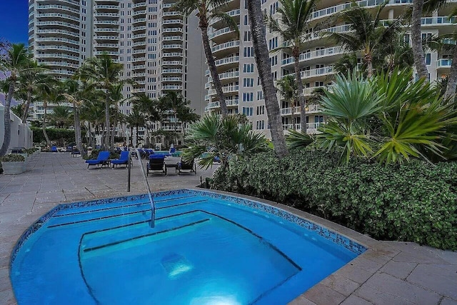 pool at dusk with a water view and a patio