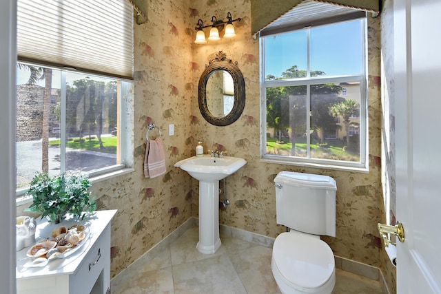 bathroom with tile patterned floors, toilet, sink, and a wealth of natural light