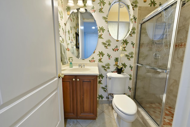 bathroom featuring tile patterned flooring, vanity, toilet, and a shower with door