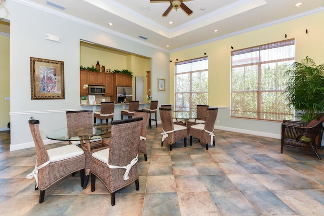 dining space featuring a raised ceiling, ceiling fan, and crown molding