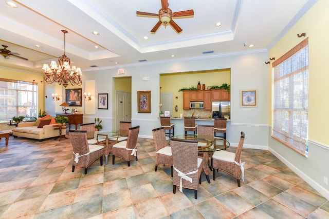 dining room featuring ceiling fan with notable chandelier, a raised ceiling, and crown molding