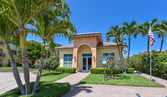 mediterranean / spanish-style home with a front yard and french doors