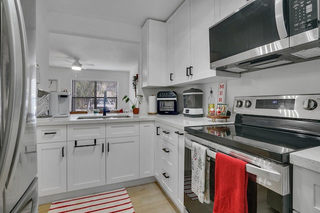 kitchen with white cabinets, light wood-type flooring, sink, and appliances with stainless steel finishes