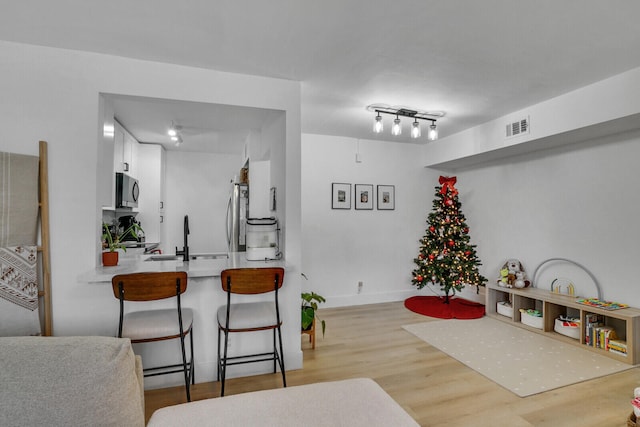 interior space featuring sink, light wood-type flooring, white cabinetry, kitchen peninsula, and stainless steel appliances