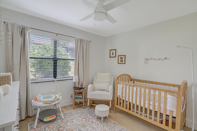 bedroom with ceiling fan, light hardwood / wood-style flooring, and a crib