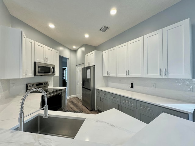 kitchen with dark wood-type flooring, white cabinets, sink, decorative backsplash, and appliances with stainless steel finishes