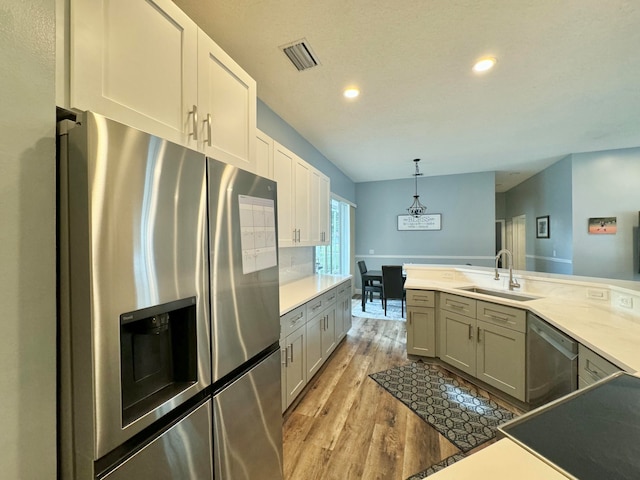 kitchen with sink, hanging light fixtures, stainless steel appliances, light hardwood / wood-style flooring, and gray cabinets