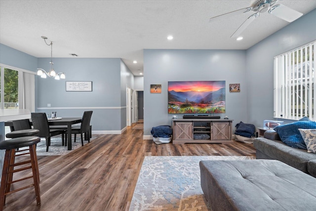 living room featuring hardwood / wood-style floors, ceiling fan with notable chandelier, and a textured ceiling