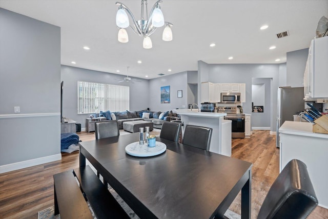 dining space featuring light hardwood / wood-style flooring and ceiling fan with notable chandelier