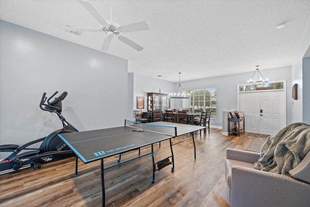 rec room with hardwood / wood-style floors, ceiling fan with notable chandelier, and a textured ceiling