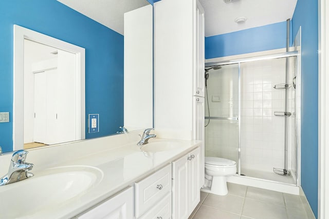 bathroom with toilet, vanity, tile patterned floors, and a shower with shower door