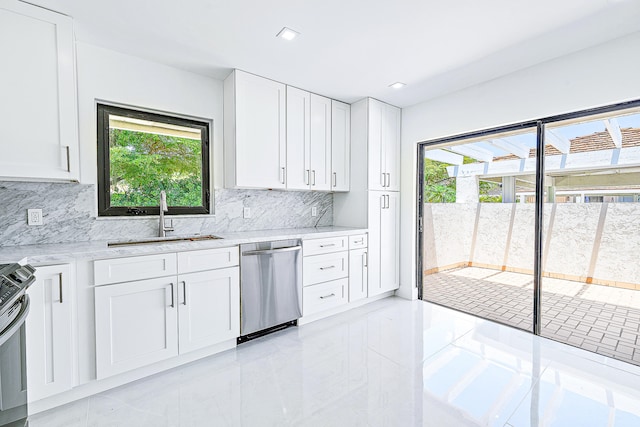 kitchen with decorative backsplash, light stone countertops, stainless steel appliances, sink, and white cabinetry