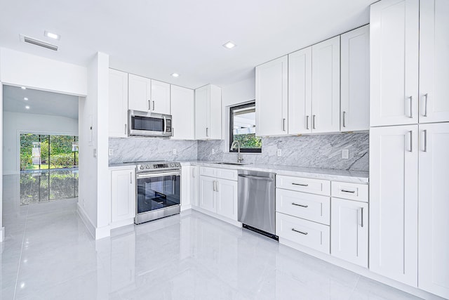 kitchen featuring white cabinets, sink, stainless steel appliances, and tasteful backsplash