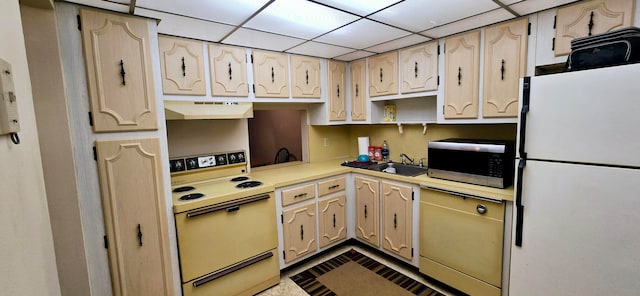 kitchen with a drop ceiling, extractor fan, sink, white refrigerator, and range with electric stovetop