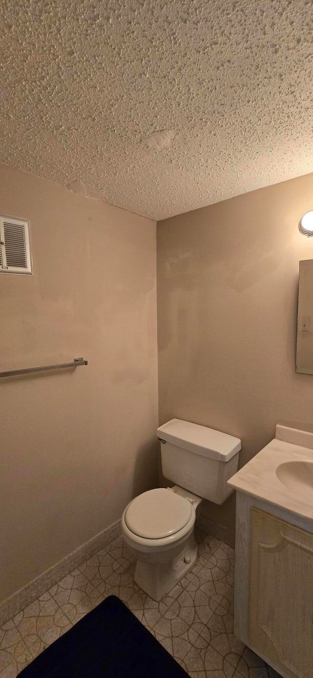 bathroom featuring tile patterned floors, vanity, toilet, and a textured ceiling