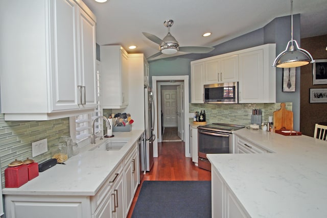 kitchen with appliances with stainless steel finishes, backsplash, dark hardwood / wood-style flooring, sink, and hanging light fixtures