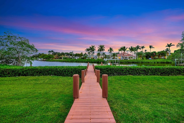 view of dock with a yard and a water view