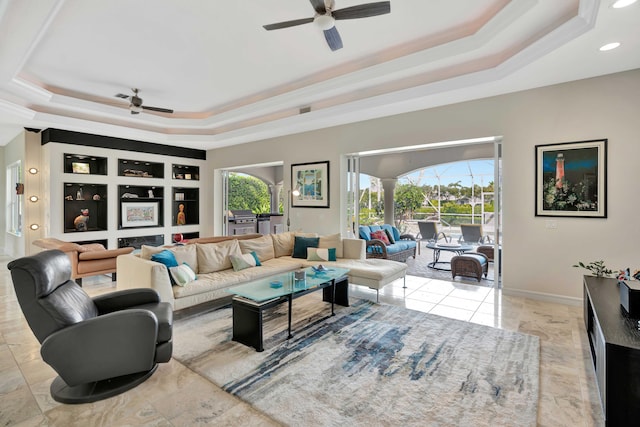 living room with a tray ceiling, ceiling fan, and a healthy amount of sunlight