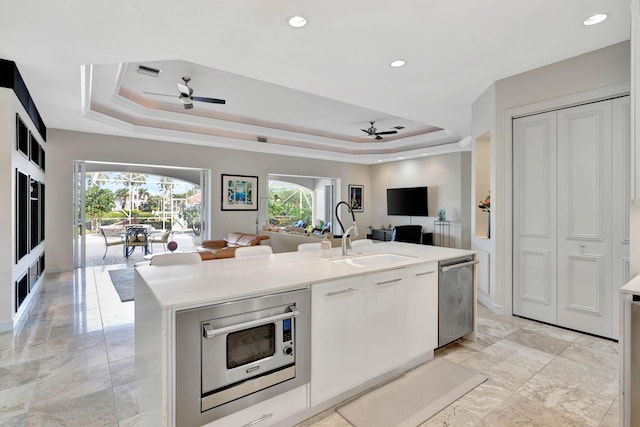 kitchen featuring white cabinets, ceiling fan, a kitchen island with sink, and appliances with stainless steel finishes