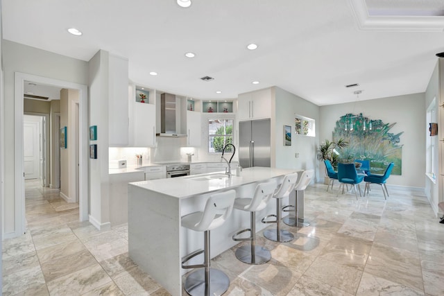 kitchen featuring sink, wall chimney range hood, decorative light fixtures, white cabinets, and appliances with stainless steel finishes