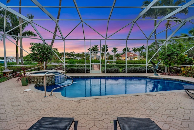 pool at dusk featuring a patio area, a lanai, and an in ground hot tub