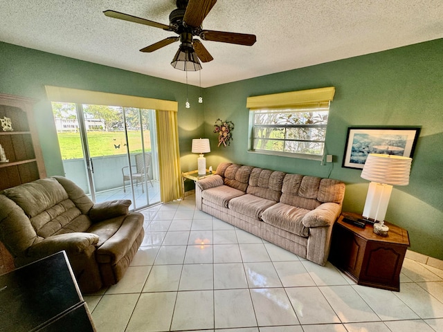 living room with ceiling fan, light tile patterned floors, and a textured ceiling