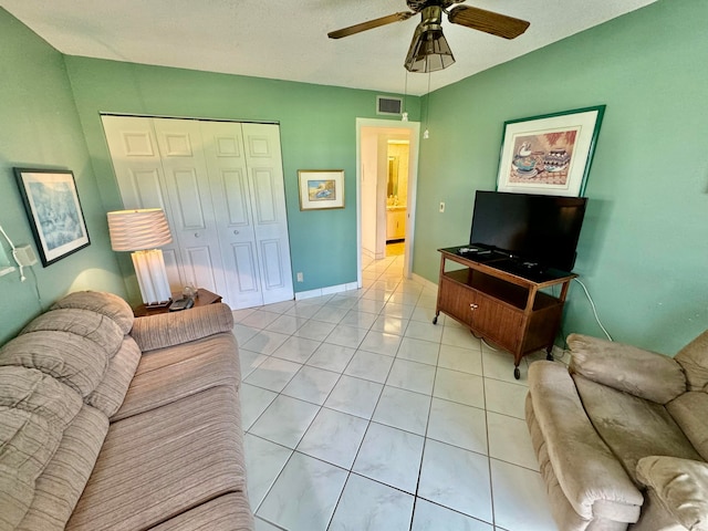 living room with ceiling fan, light tile patterned floors, and a textured ceiling