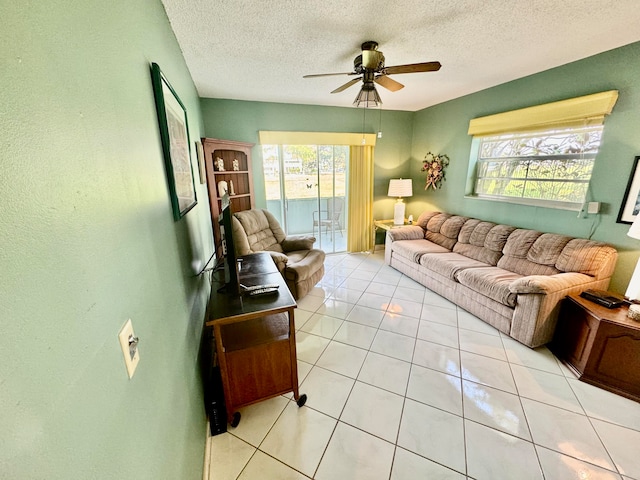 tiled living room featuring ceiling fan, a healthy amount of sunlight, and a textured ceiling