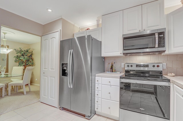 kitchen with white cabinets, appliances with stainless steel finishes, backsplash, and light tile patterned floors