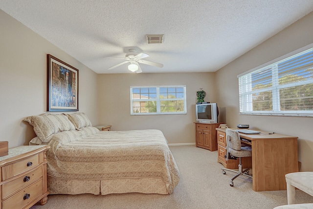 bedroom with ceiling fan, light colored carpet, and a textured ceiling