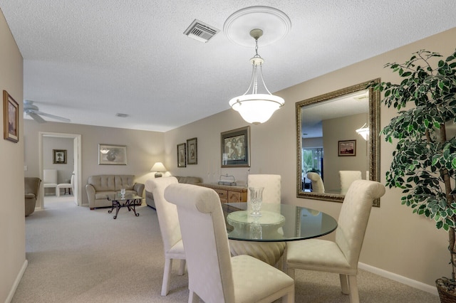 dining space featuring a textured ceiling, light colored carpet, and ceiling fan