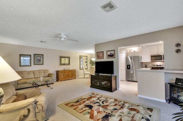 living room with ceiling fan, a textured ceiling, and light carpet