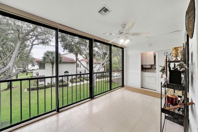 unfurnished sunroom featuring washing machine and clothes dryer and ceiling fan