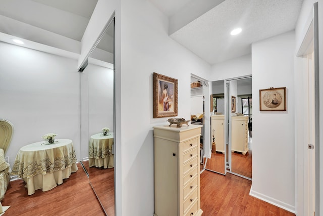 corridor featuring a textured ceiling and light hardwood / wood-style flooring