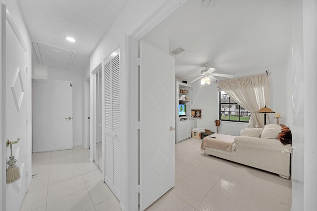 interior space featuring ceiling fan, light tile patterned floors, and a textured ceiling