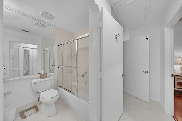 bathroom featuring tile patterned flooring, bath / shower combo with glass door, and toilet