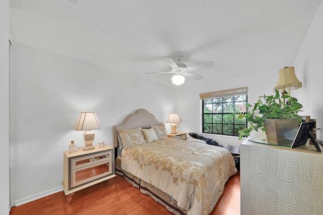 bedroom featuring ceiling fan, wood-type flooring, and a textured ceiling