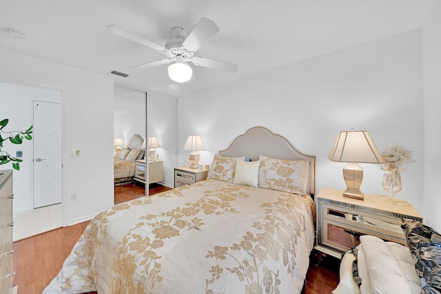 bedroom with ceiling fan, a closet, and dark wood-type flooring