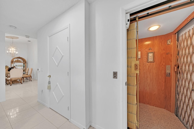 hall featuring light tile patterned floors, an inviting chandelier, and wood walls