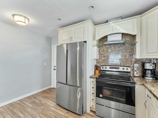 kitchen with cream cabinetry, stainless steel appliances, light hardwood / wood-style flooring, and dark stone countertops