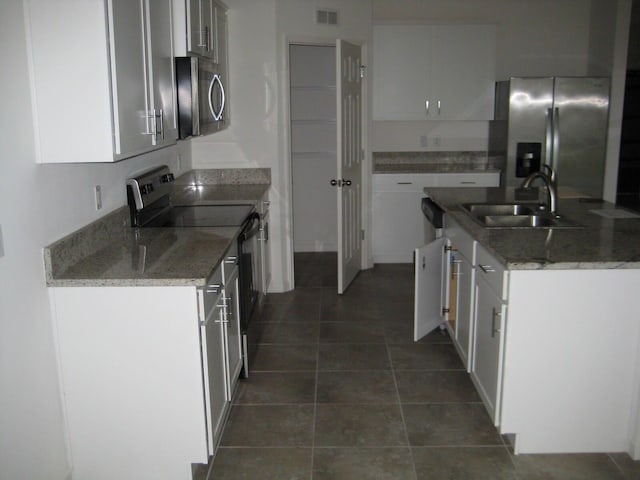 kitchen with white cabinets, appliances with stainless steel finishes, light stone countertops, and sink