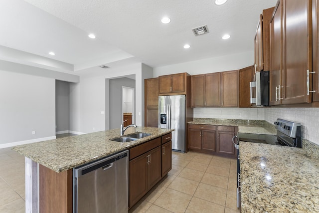 kitchen with sink, decorative backsplash, a textured ceiling, appliances with stainless steel finishes, and an island with sink