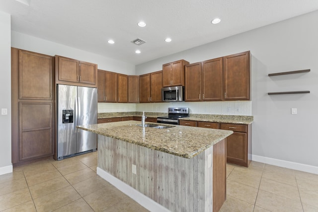 kitchen featuring appliances with stainless steel finishes, light stone counters, a kitchen island with sink, sink, and light tile patterned floors